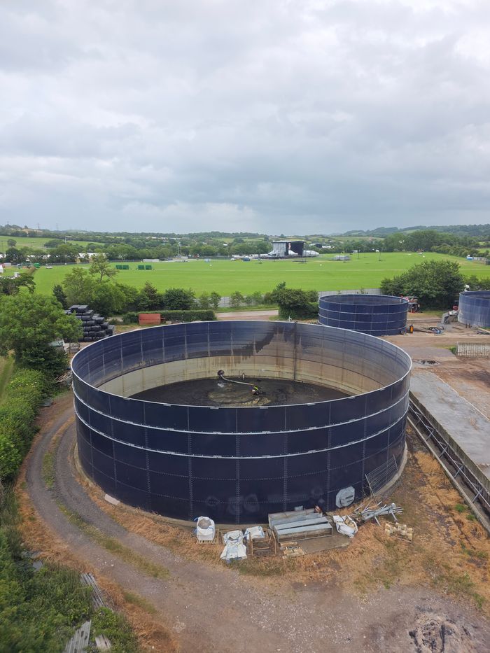 Overhead shot of large round water storage tanks in a green landscape.
